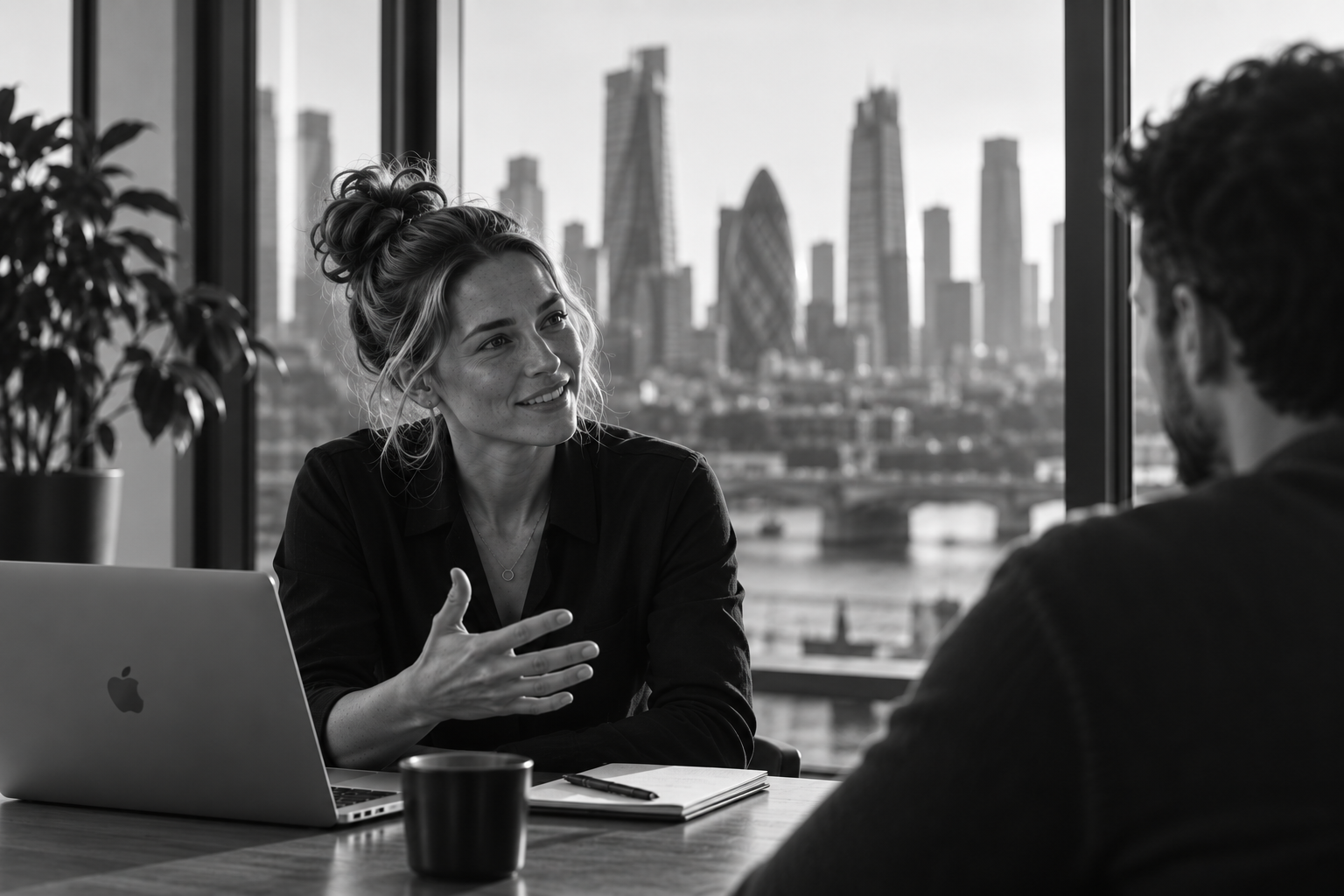 A coach in conversation across a table with the London skyline behind them